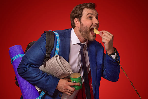 man eating Pringles and carrying a large amount of luggage